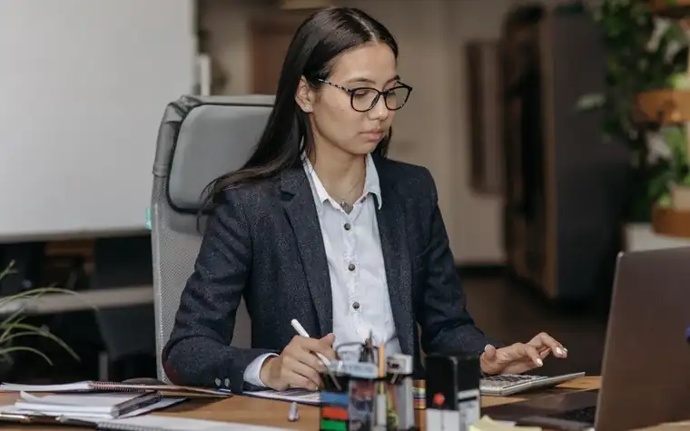 책상에서 노트북과 서류로 급여를 확인하는 사무직 여성