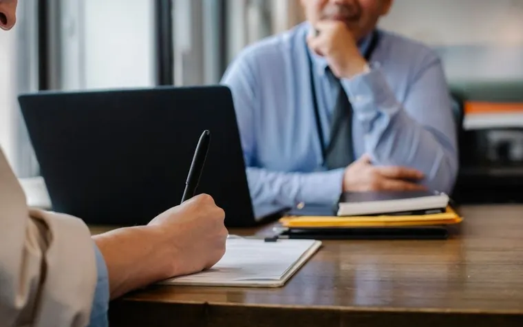 A person in a suit at a desk holding documents and reviewing them