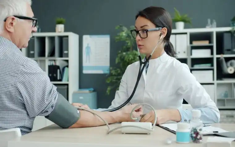 A doctor measuring an older patient's blood pressure in an examination room