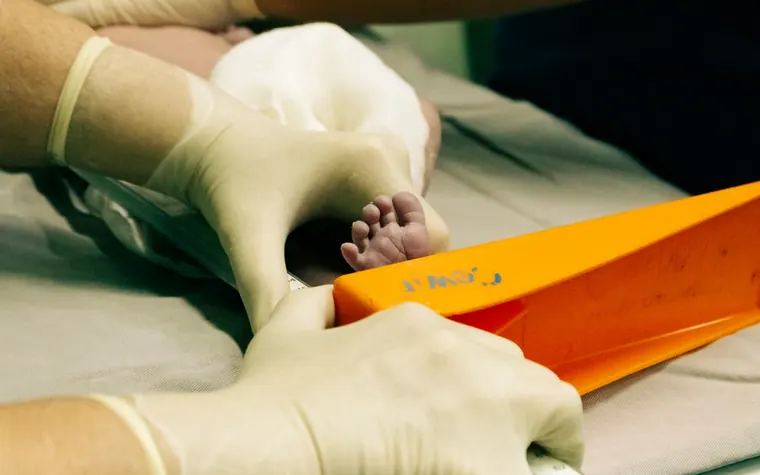 A nurse measuring the length of a newborn baby's foot