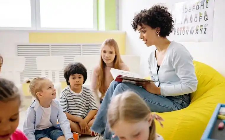 A teacher reading a picture book to children in a kindergarten classroom