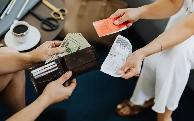 A hand pulling cash and a receipt out of a wallet