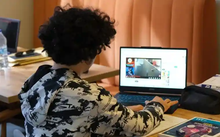 집에서 공책에 필기하며 공부하는 청소년