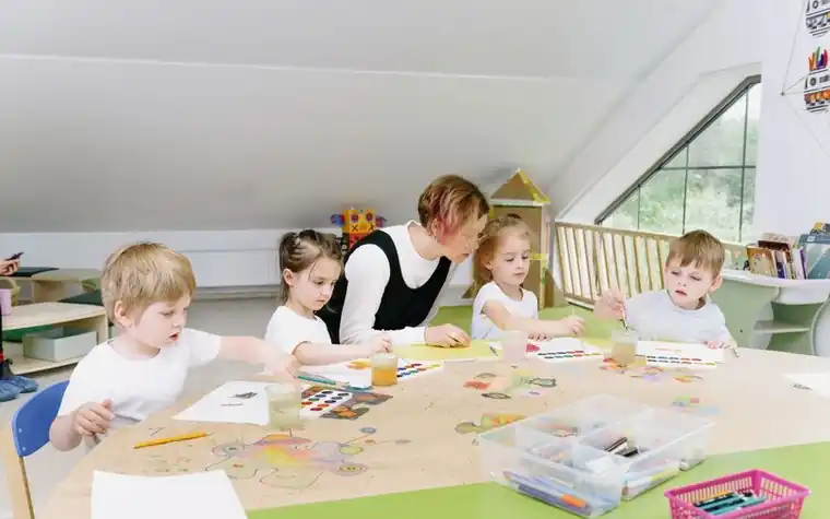 Teacher watching children do a drawing activity