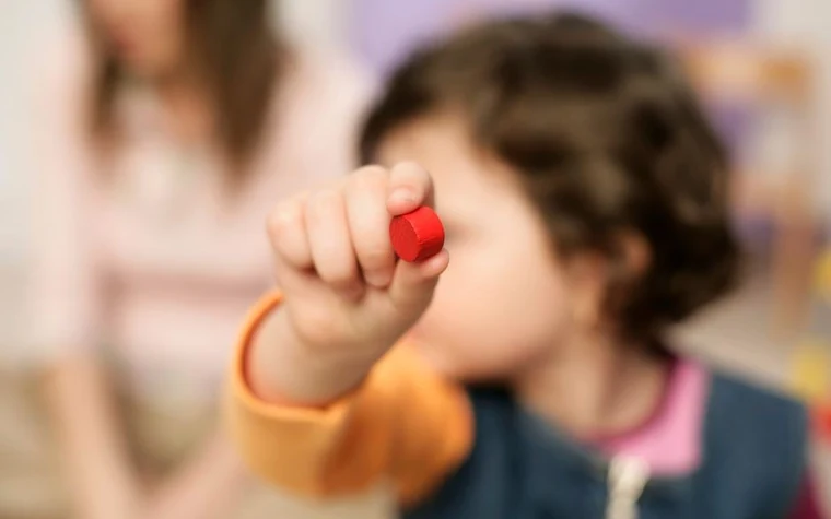 A young child holding a toy block in one hand while playing