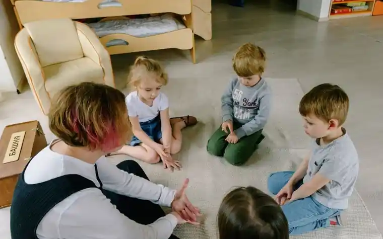 A teacher talking with children seated in a circle on a classroom floor