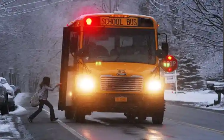 A child running toward a school bus on a snowy road