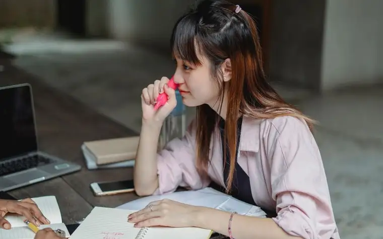 책상에서 형광펜을 입에 대고 생각에 잠긴 학생
