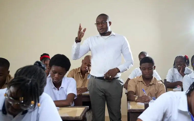 A teacher asking students a question in a classroom with high school students attending the lesson