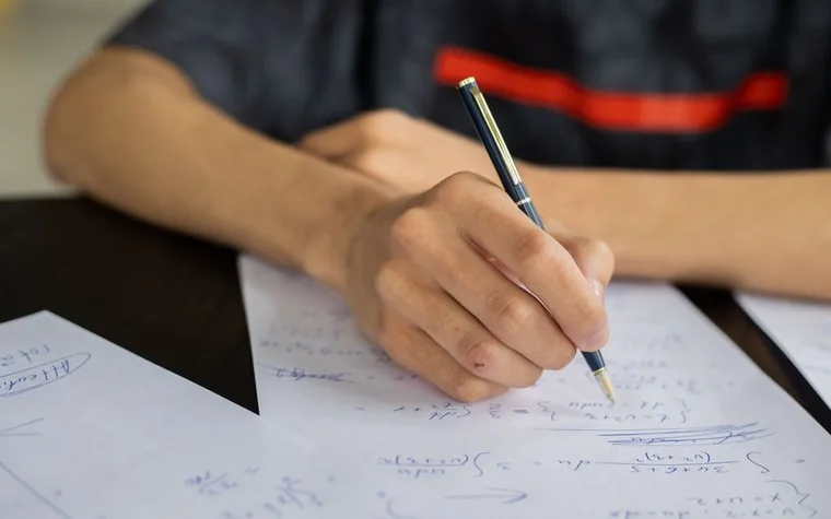 A student's hand writing while concentrating on solving problems