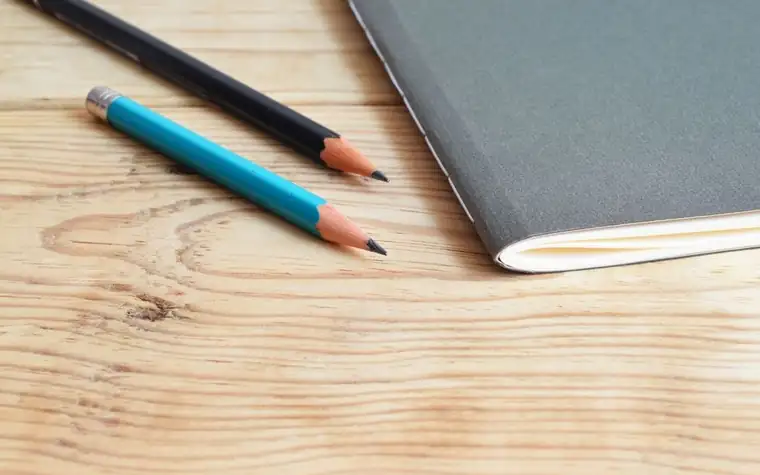 A notebook and pencils on a wooden desk