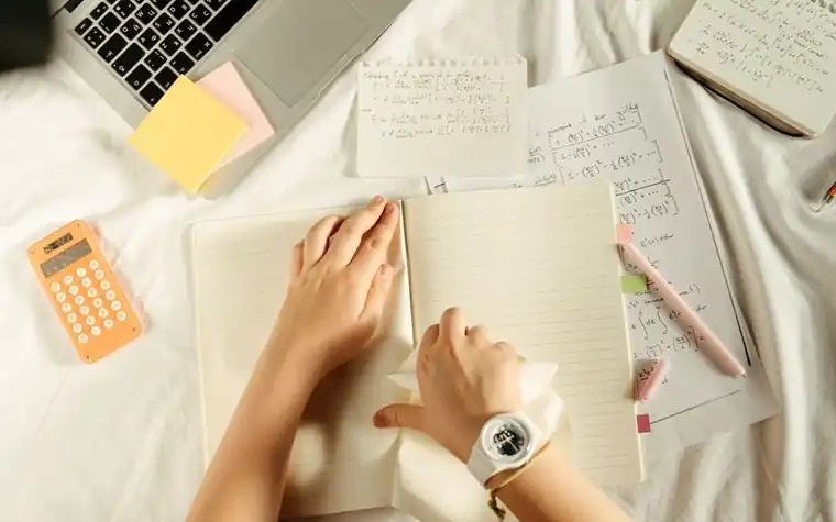 Overhead view of a desk with a laptop, a calculator and a notebook