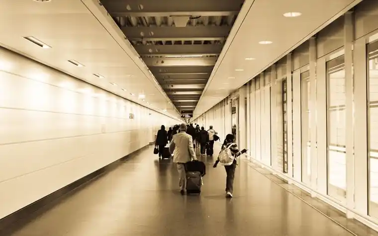 공항 통로를 여행 가방을 끌고 걸어가는 여행객들
