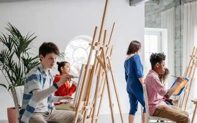 Students painting at easels in an art class