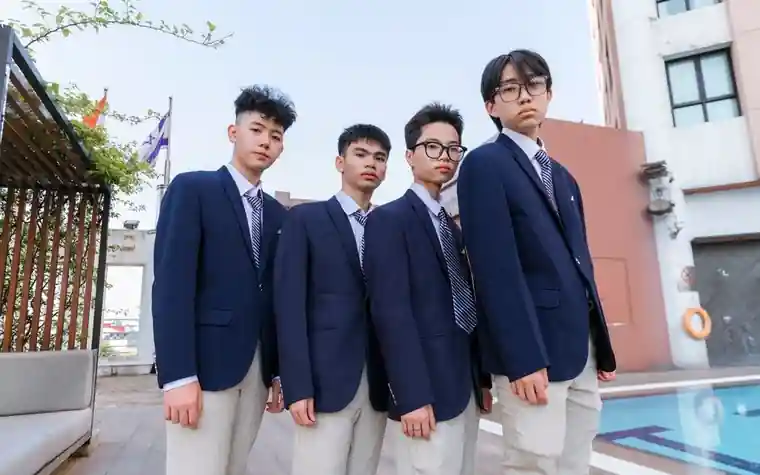 푸른 교복 재킷을 입고 야외에 선 남학생 네 명