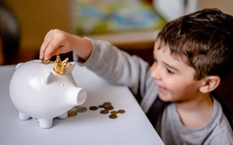 A child putting a coin into a piggy bank