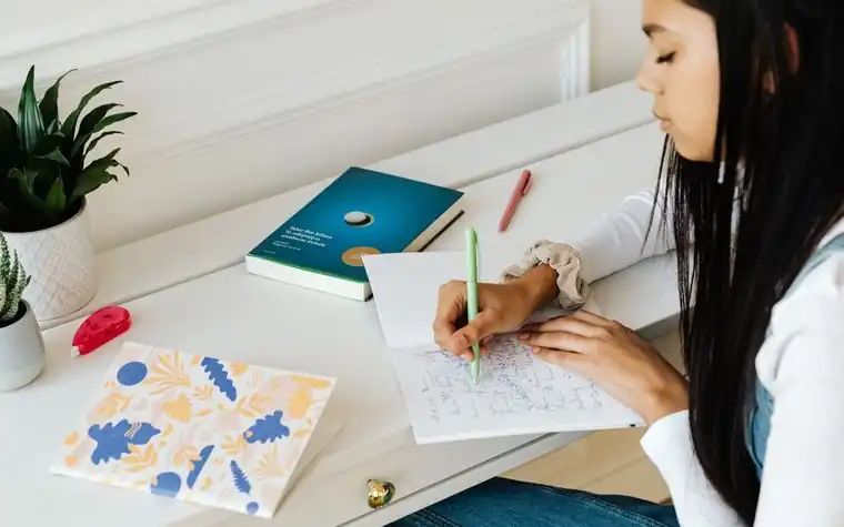 A student writing in a notebook at a desk