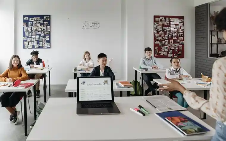여러 학생이 노트북과 교재로 함께 공부하는 교실 모습