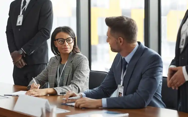 People talking across a meeting room table with documents between them