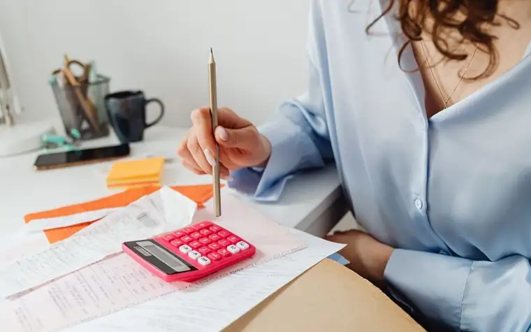 Hands working through receipts and a calculator to figure out household expenses