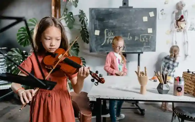 A child playing the violin in a classroom while classmates work behind