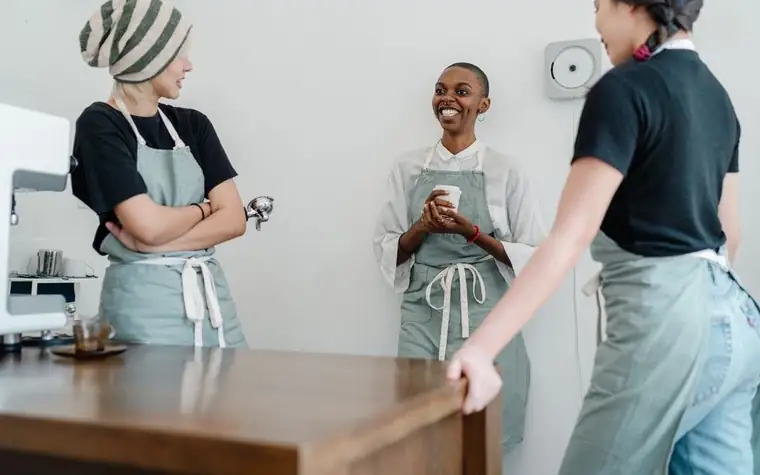 A smiling young part-time worker in an apron working in a cafe