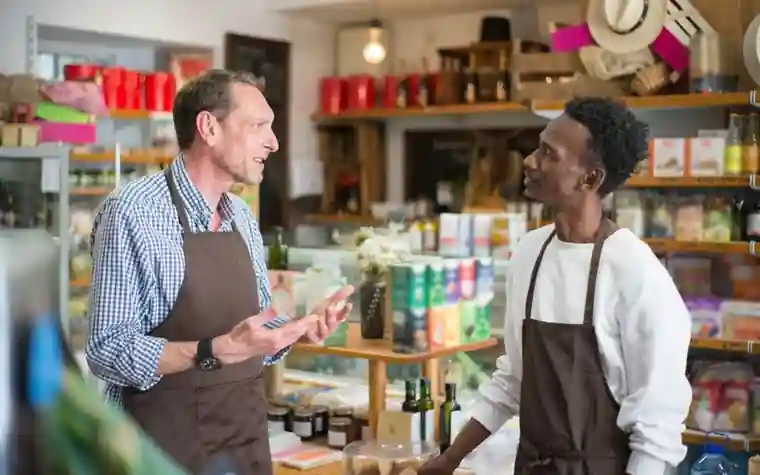 Two employees in aprons talking inside a shop