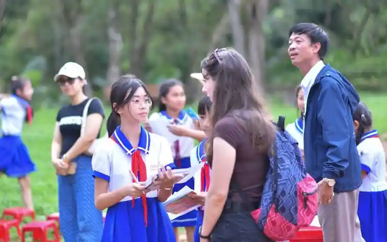 Children in school uniforms talking outdoors with adults during an activity