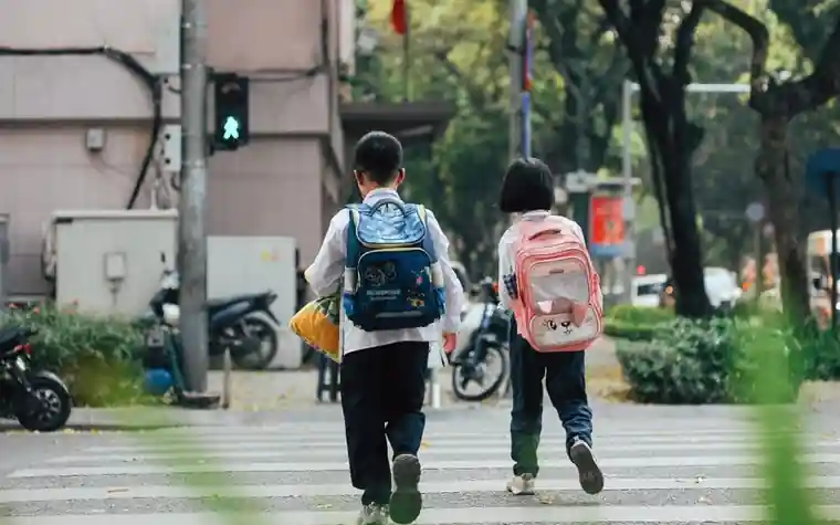 배낭을 멘 두 아이가 횡단보도를 건너는 모습